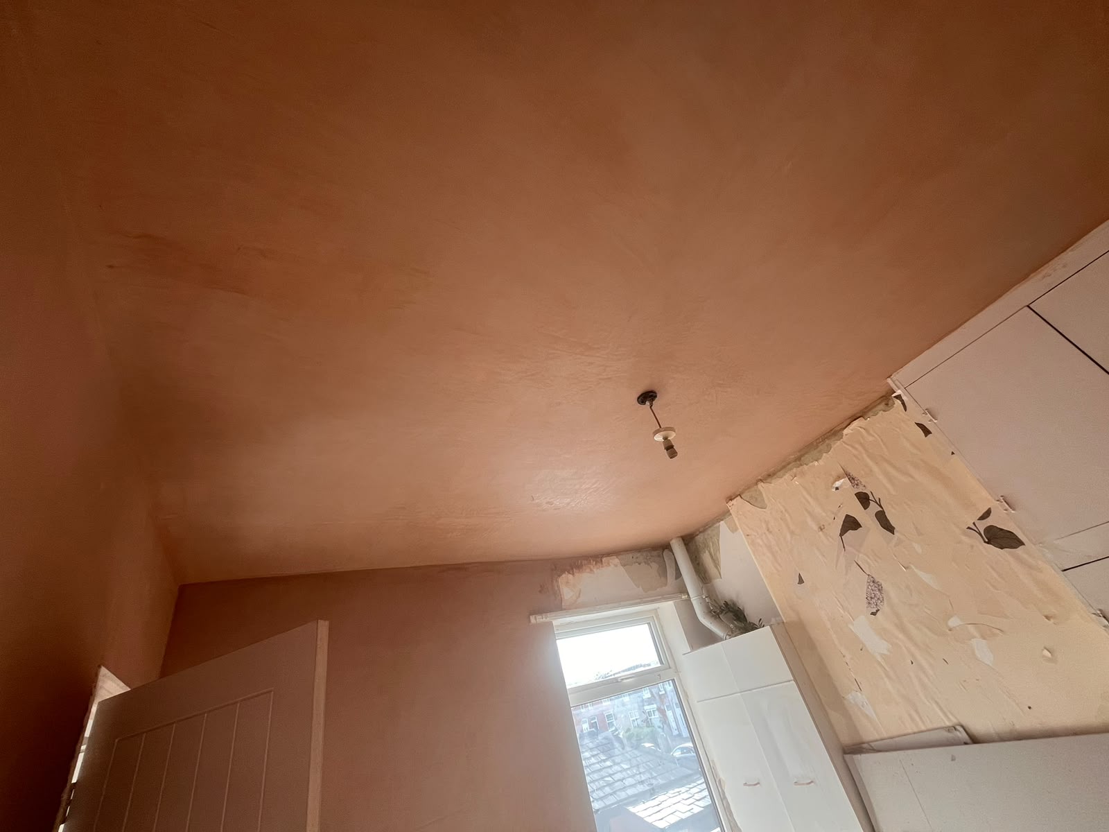 Freshly skimmed plaster ceiling with a pendant flex, looking toward a window